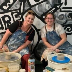 Student shaping clay on the pottery wheel at our San Diego studio.