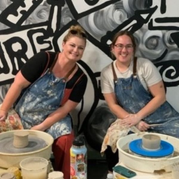 Student shaping clay on the pottery wheel at our San Diego studio.