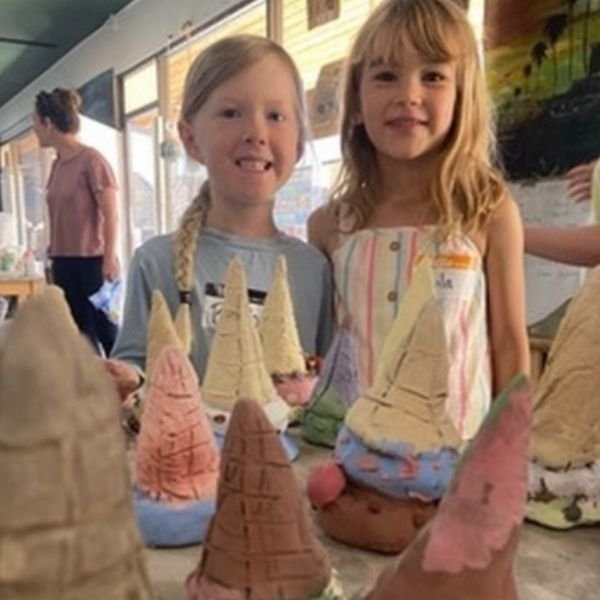 Kids smiling while hand-building clay creations at The Pottery Outpost.