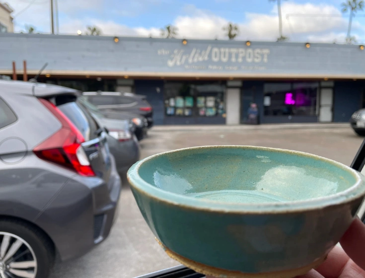 Handcrafted ceramic bowl held up in front of The Artist Outpost in San Diego, made by a satisfied pottery student.