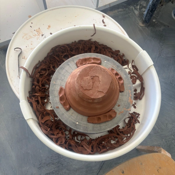 Upside-down bowl secured with clay keys while trimming the foot on a pottery wheel